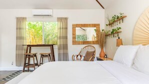 A bedroom with a large bed, a desk with two stools, a chair, a mirror, and a wall-mounted plant shelf. - Private 420 Pool & Spa Bungalow: Botanical Oasis (Los Angeles)