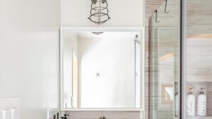A bathroom with a white vanity, a mirror, and a glass shower enclosure. - Private 420 Pool & Spa Bungalow: Botanical Oasis (Los Angeles)