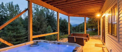 A hot tub under a wooden pergola with a view of trees and a mountain in the background.