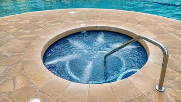 A hot tub with a stone surround and a metal ladder.