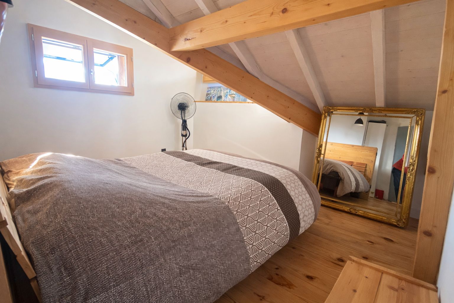 Una camera da letto con un letto, una ventola, una finestra e uno specchio.