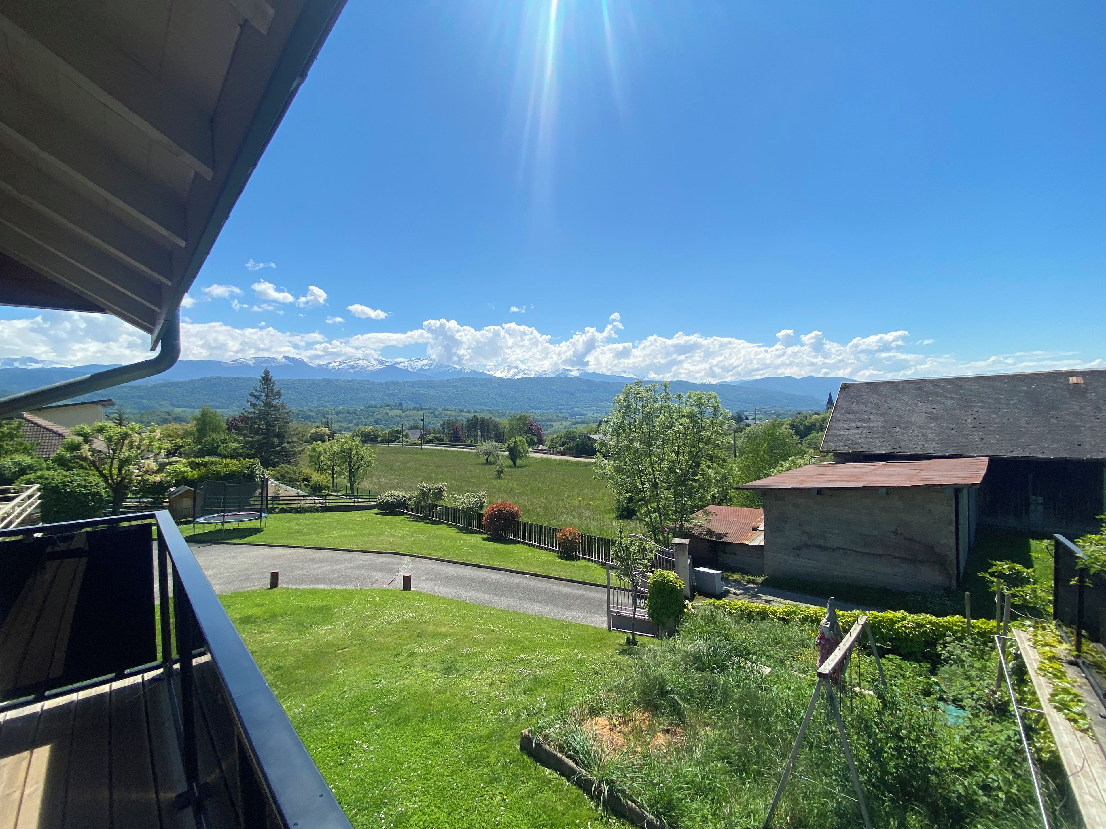 A residential property with a view of mountains, a fenced yard, and a road.