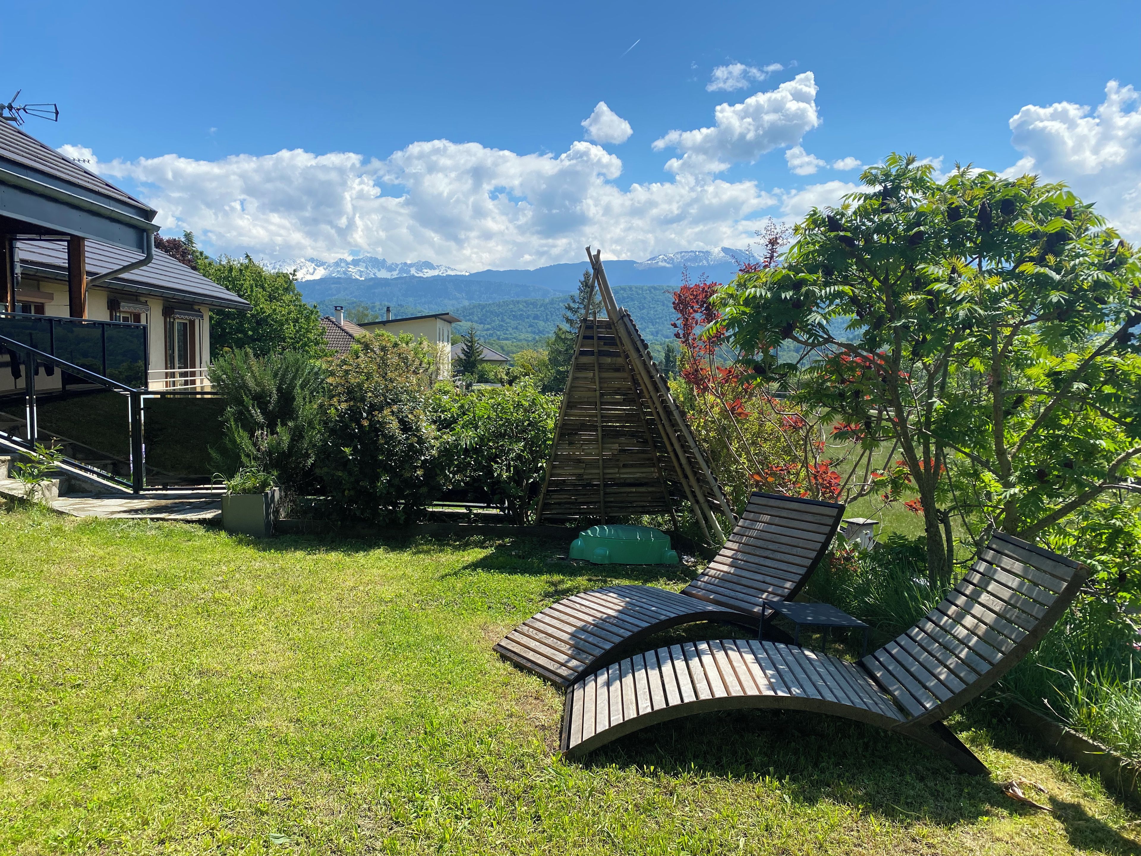 A backyard with a wooden deck, a small pool, and a view of mountains.
