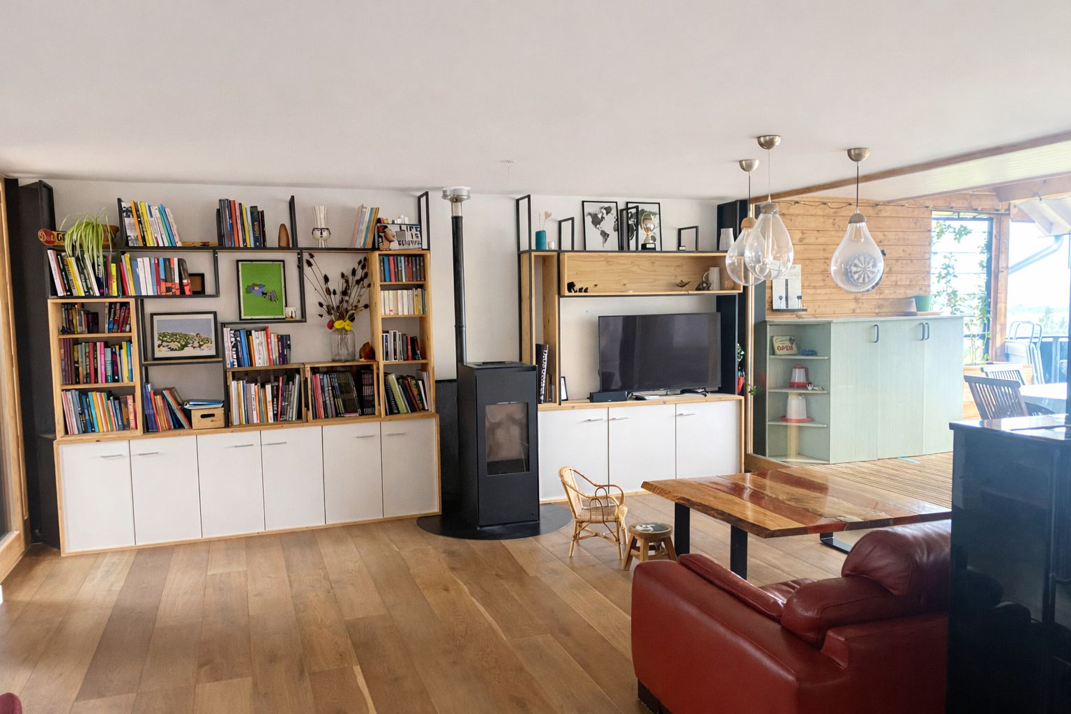 Una sala moderna con chimenea, estanterías, televisor y comedor.