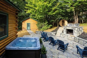 Eine Holzhütte mit Whirlpool, Sitzgelegenheiten im Freien und einem Steinkamin.