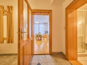 Ein Flur mit Holztüren, Fliesenboden und Blick in einen Essbereich mit Tisch und Stühlen.