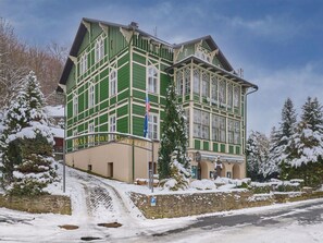 En bygning med flere etager, en grøn facade og en stensokkel, med en markant indgang og trappe.