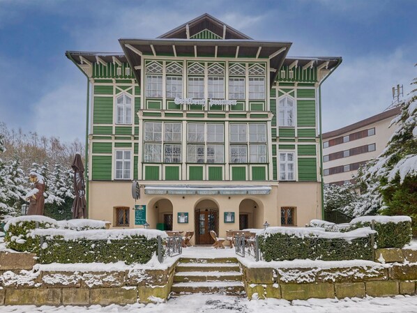 Un edificio con fachada verde, varias ventanas y un letrero que dice 'Café'.