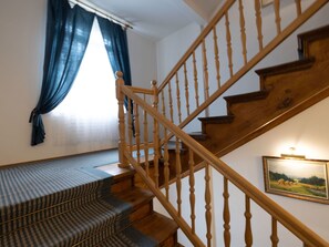A wooden staircase with a handrail, carpeted steps, and a window with blue curtains. - Cosy apartment for 3 people with WIFI, TV, patio and pets allowed (Trutnov)