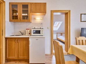 Eine kleine Küche mit Holzausstattung, einer Mikrowelle und einem Kühlschrank.