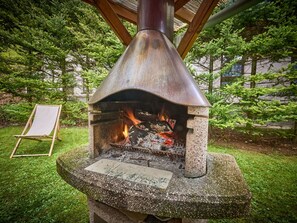 A stone-built outdoor pizza oven with a chimney, surrounded by greenery. - Nice apartment for 3 guests with WIFI, TV, patio and pets allowed (Trutnov)