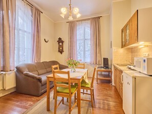 Un salon confortable avec un canapé, une table à manger avec des chaises, un coin cuisine avec un réfrigérateur et une grande fenêtre avec des rideaux.