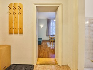 A hallway with a wooden door, a wall-mounted coat rack, a small table with chairs, and a tiled floor. - Nice apartment for 3 guests with WIFI, TV, patio and pets allowed (Trutnov)