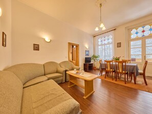 Ein Wohnzimmer mit einer Couch, einem Couchtisch, einem Fernseher und einem Essbereich mit Stühlen und einem Tisch.