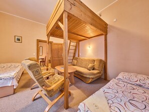 Ein gemütliches Zimmer mit Holzbalkendecke, einer Couch, einem Sessel und einem kleinen Tisch.