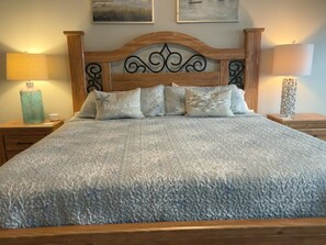 Ein Bett mit einer strukturierten Decke, einem Holzkopfteil und Nachttischlampen.