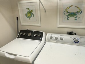 A laundry area with two washing machines and two framed pictures of sea creatures on the wall. - Beachfront Townhouse(22) Pet Friendly Covered Deck (Panama City)