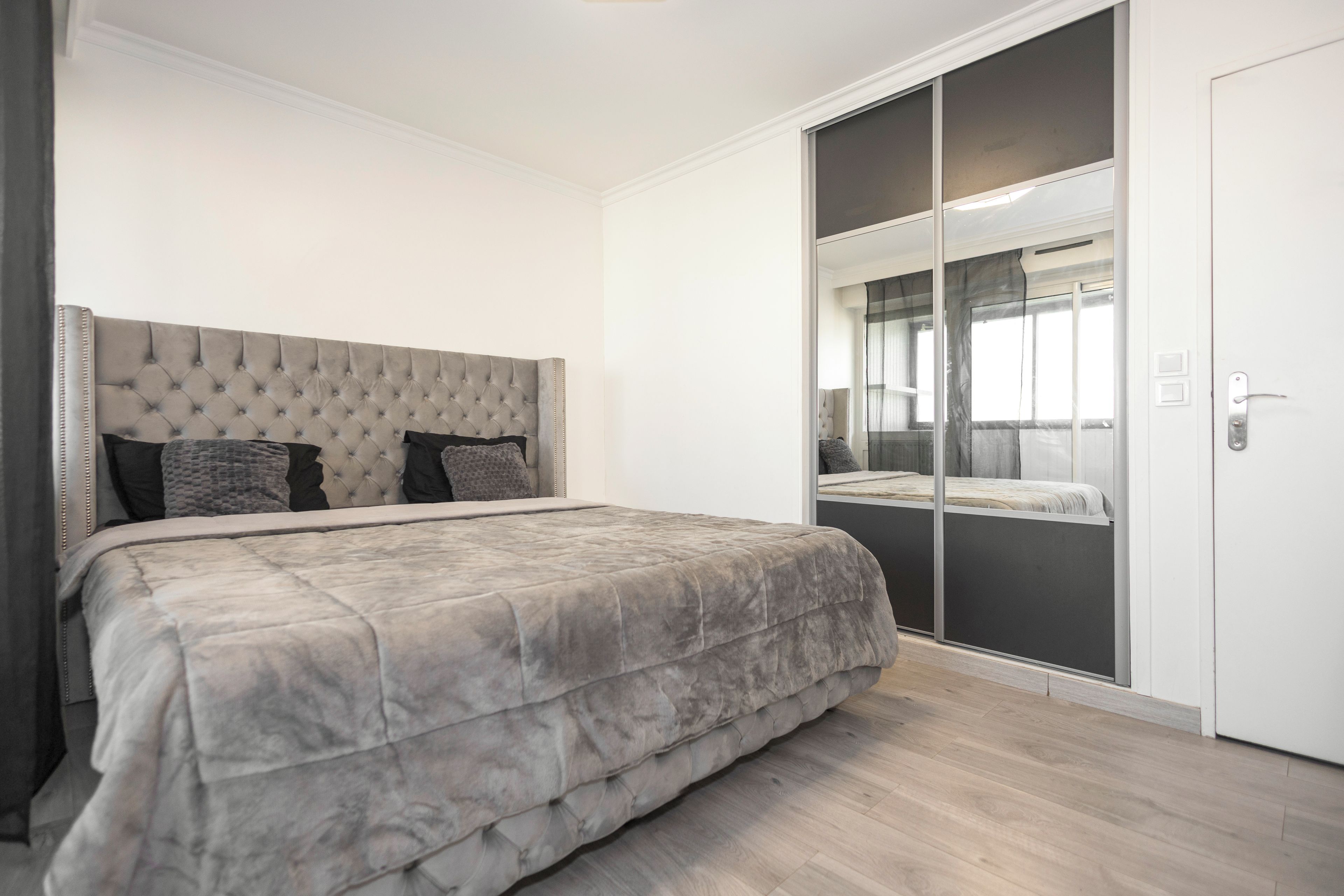 Een slaapkamer met een groot bed, een kledingkast met spiegel en een schuifdeurkast.