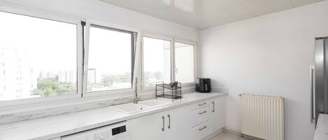 A modern kitchen with a built-in washing machine, a sink, and a window overlooking a cityscape.