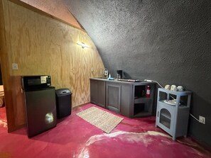 Cozinha compacta com micro-ondas, pia e armário pequeno.
