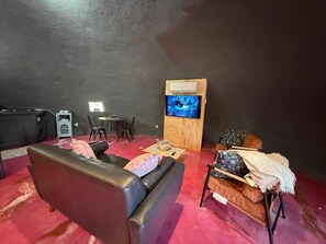 A living room with a leather sofa, a small round table, and a television mounted on a wooden stand. - Purple Dome : One of Kind Geodesic Dome for two (Van Alstyne)