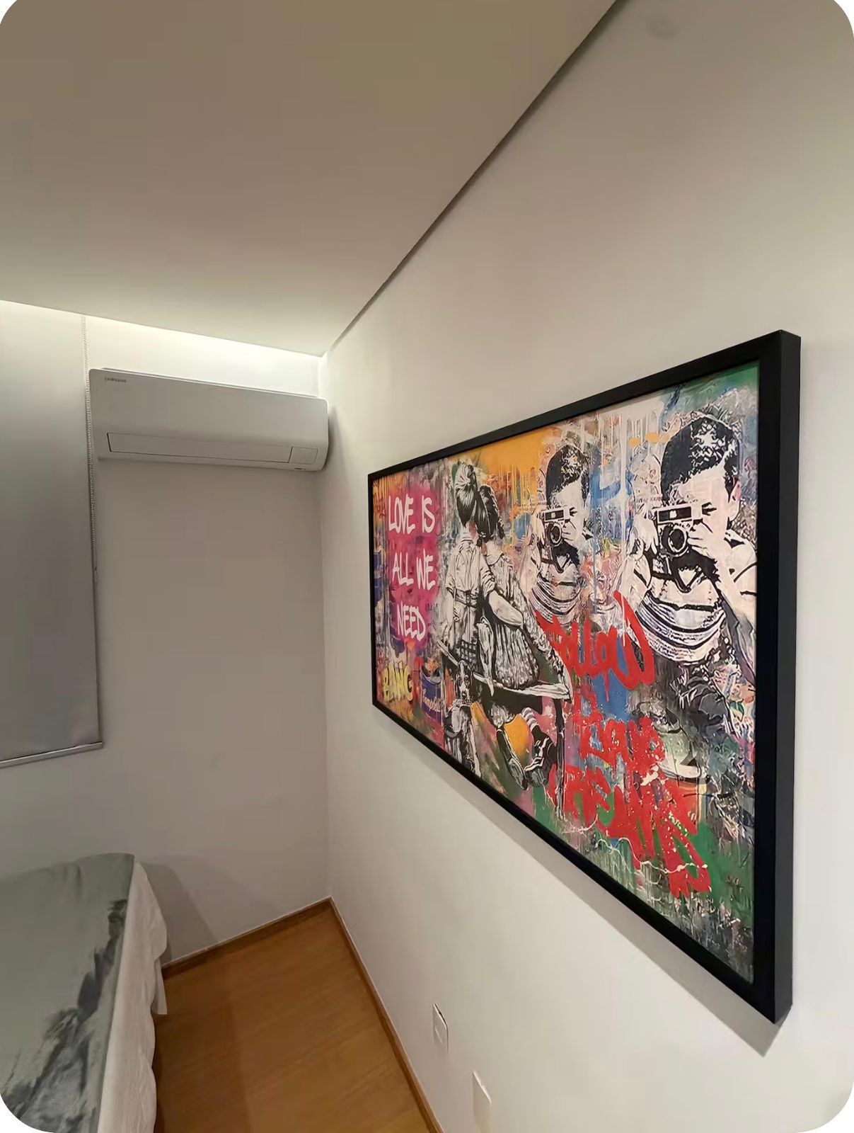 Una habitación con un cuadro grande y llamativo en la pared, un equipo de aire acondicionado blanco y suelo de madera.