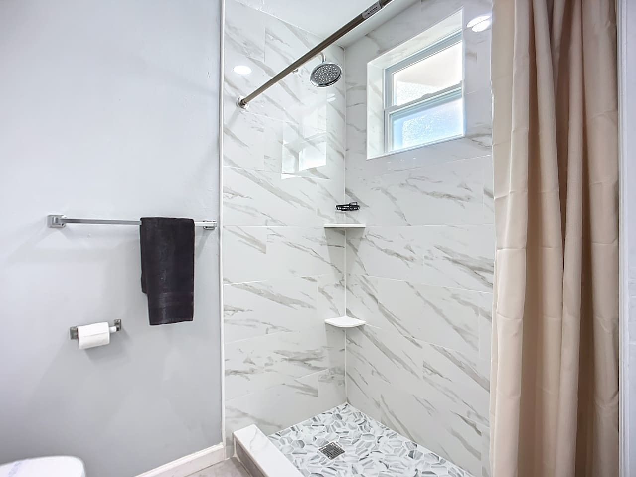 A bathroom with a shower, a towel rack, and a toilet.