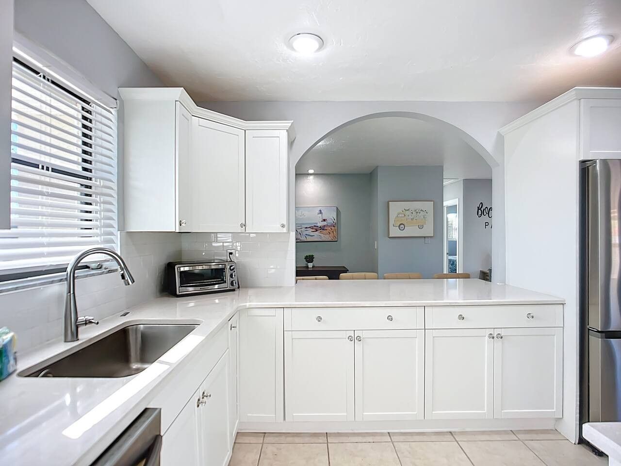 A modern kitchen with white cabinetry, a stainless steel sink, and a built-in oven.