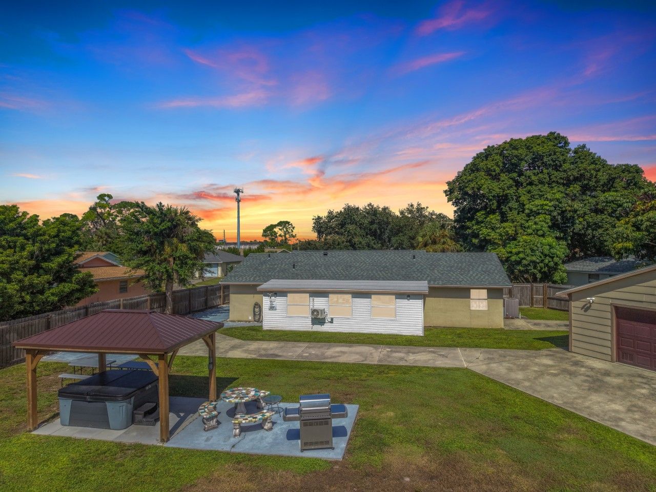 A residential property with a covered patio, a garage, and a house with a sloped roof.