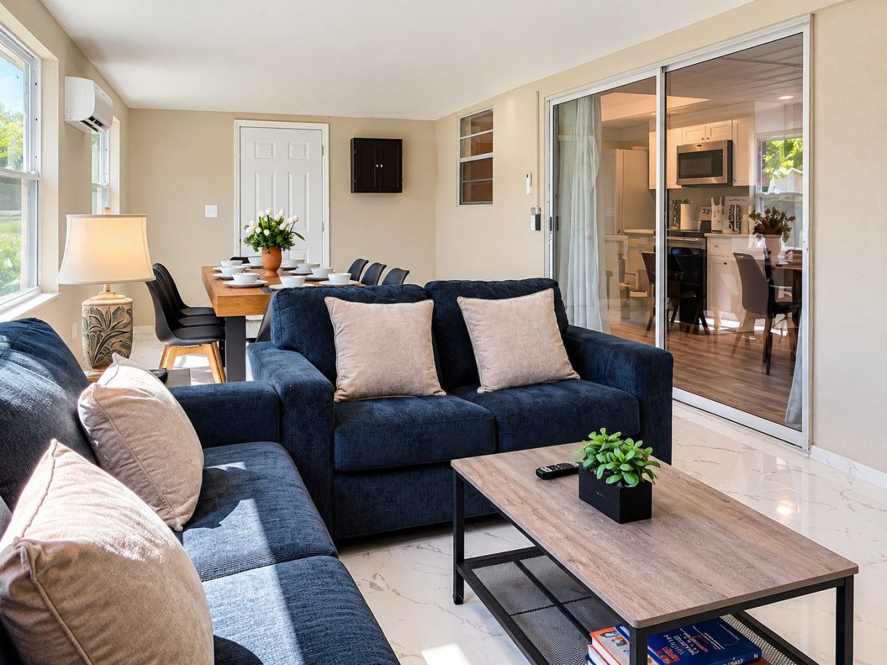 A modern living room with a sofa, a coffee table, and a dining area with chairs and a table.