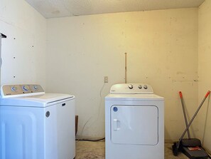 Een wasserette met twee witte wasmachines, een bezem en een hark.