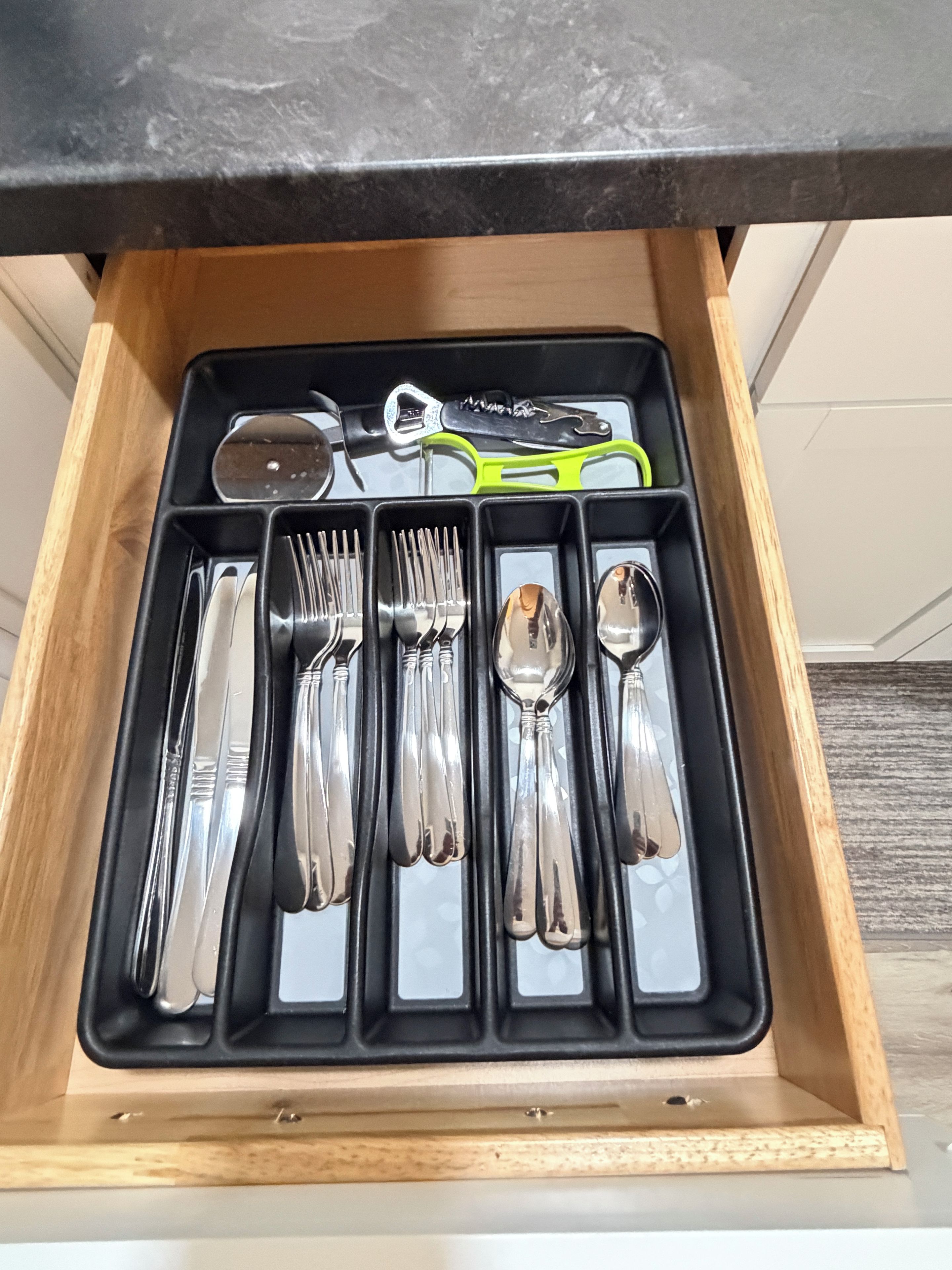 Un cajón con cubiertos, incluyendo tenedores, cuchillos y cucharas.