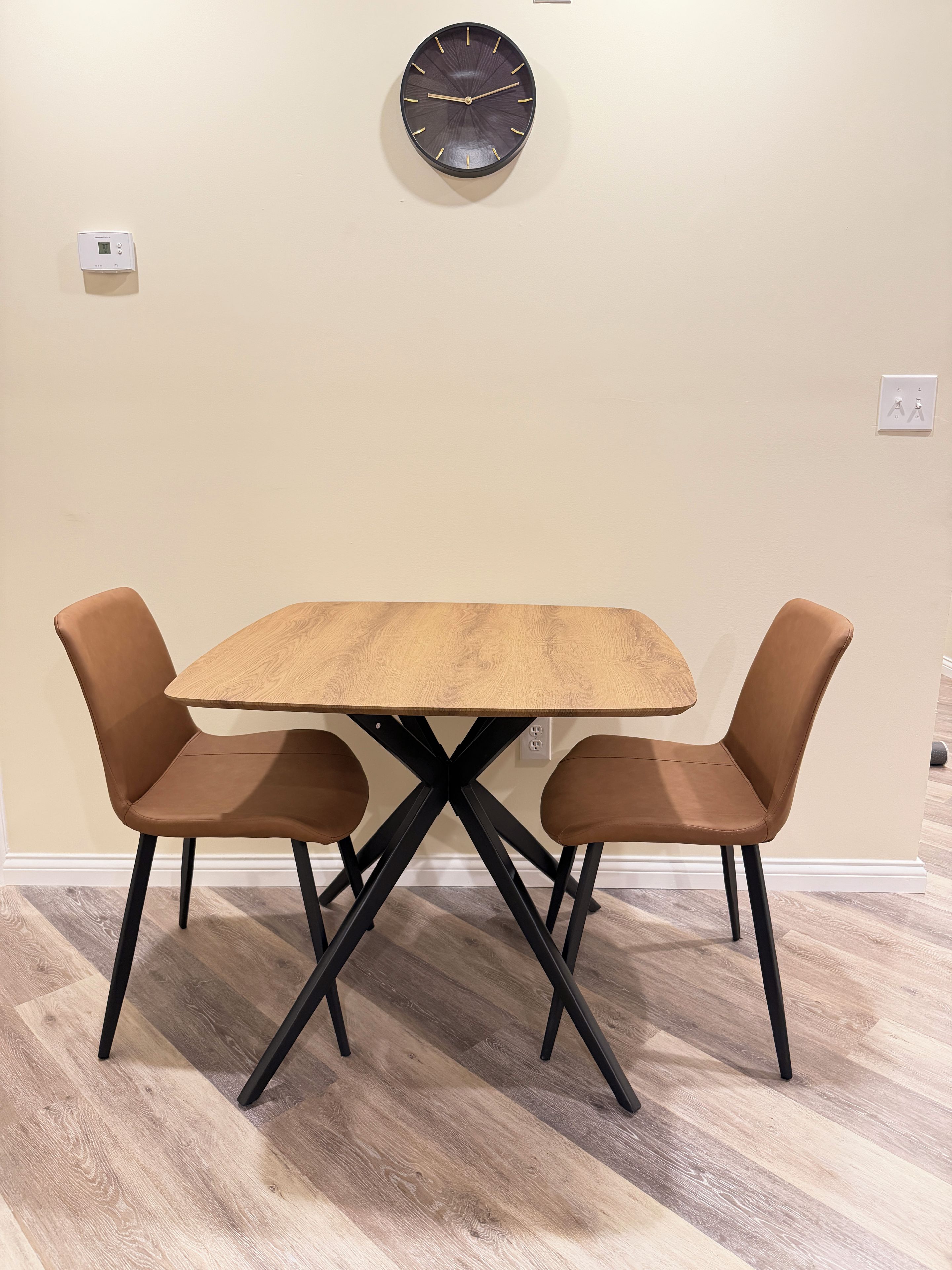 Un'area pranzo con tavolo e sedie, una sveglia a parete e un termostato.