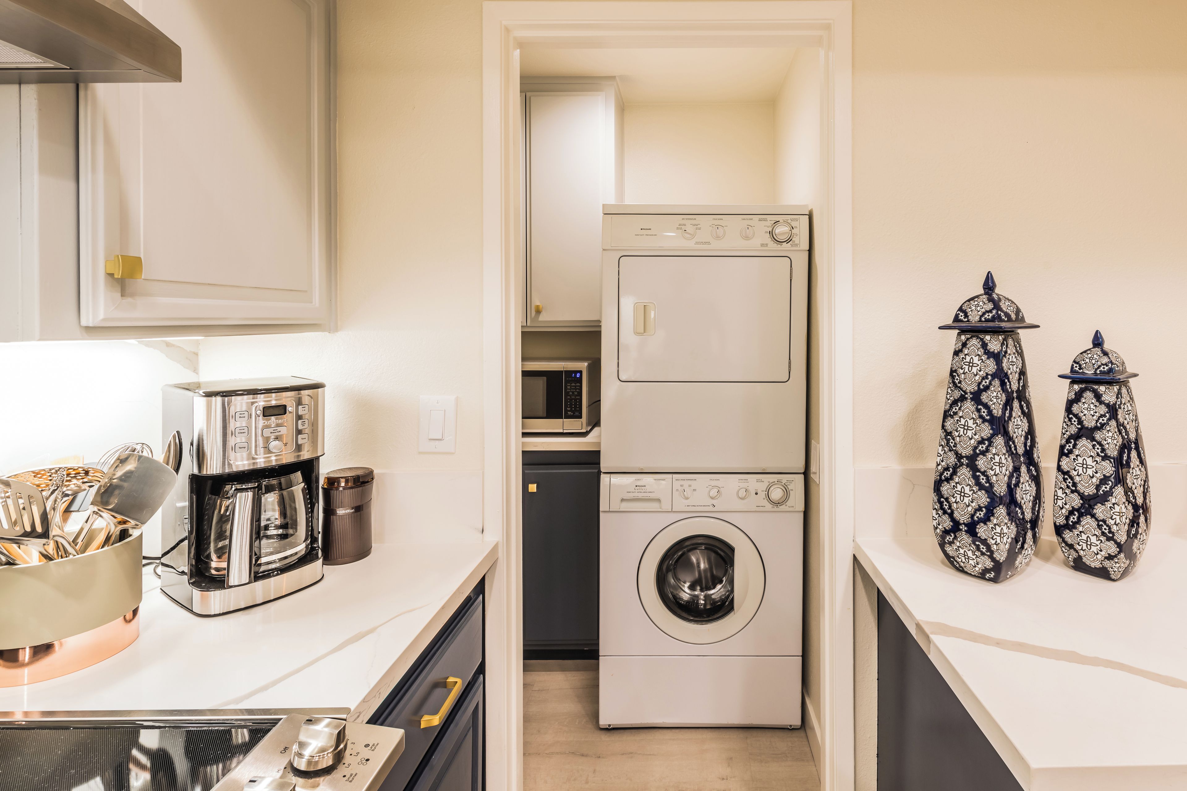 Une cuisine compacte équipée d’une machine à café, d’un four à micro-ondes et d’un lave-linge.