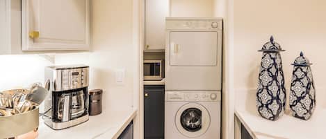 Une cuisine compacte équipée d’une machine à café, d’un four à micro-ondes et d’un lave-linge.