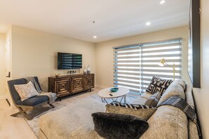 A modern living room with a sofa, a chair, a coffee table, and a TV mounted on the wall. - Casa Allure - A Ryson Property (Palm Springs)