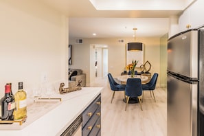 A modern kitchen with a central island, a dining area with a chandelier, and a large refrigerator. - Casa Allure - A Ryson Property (Palm Springs)