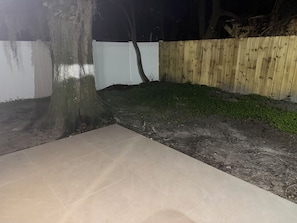 A paved patio area with a tree and a wooden fence. - Cozy getaway in Orlando (Orlando)