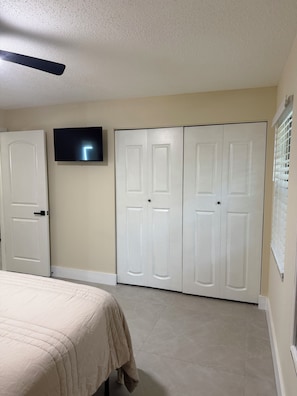 A bedroom with a bed, a television, and a set of white doors. - Cozy getaway in Orlando (Orlando)