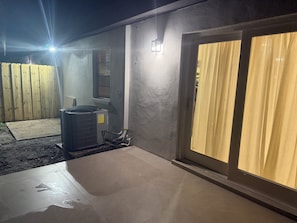 An outdoor patio area with a tiled floor, a wooden fence, and a sliding glass door with curtains. - Cozy getaway in Orlando (Orlando)