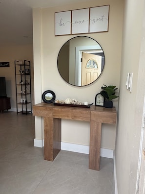 A wooden console table with a mirror above it, a decorative tray, and a potted plant. - Cozy getaway in Orlando (Orlando)
