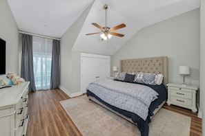A bedroom with a bed, a nightstand, a ceiling fan, a dresser, and a window with curtains. - Brand New Listing, Beach, Pool, 2 K Beds (Mexico Beach)