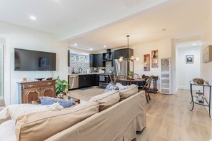 Un salon moderne comprenant un canapé, un téléviseur à écran plat et un coin repas avec des chaises et une table.