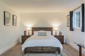 A bedroom with a wooden bed, two bedside tables with lamps, a window with curtains, and two framed pictures on the wall. - Beautiful 1-Bedroom Unit - Quiet Neighborhood & Close Access to Vibrant Downtown (San Rafael)