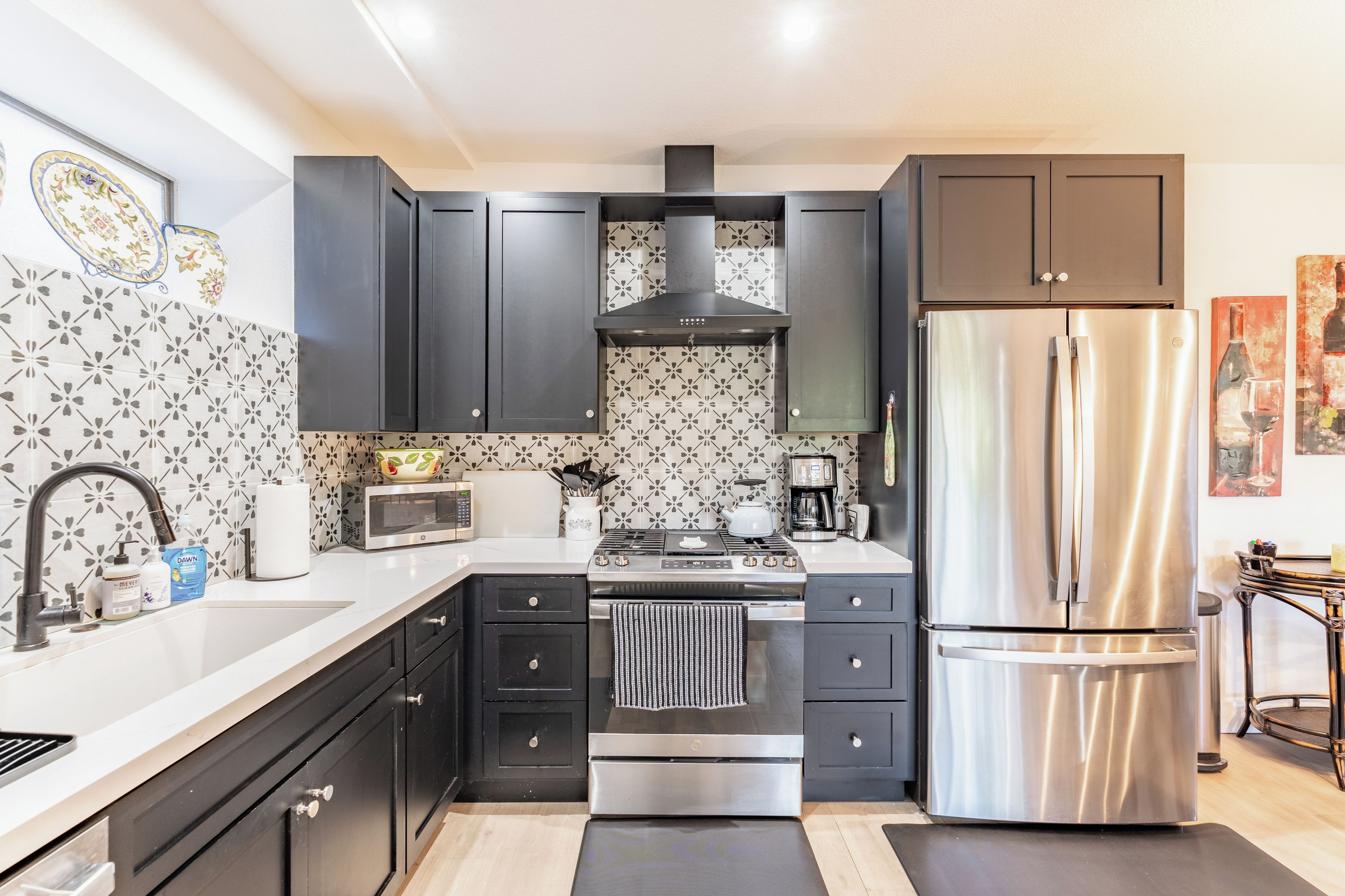 A modern kitchen with dark cabinetry, a stainless steel refrigerator, a microwave, and a gas stove.