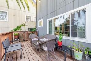 A wooden deck with wicker furniture, potted plants, and a view of the building's exterior. - Beautiful 1-Bedroom Unit - Quiet Neighborhood & Close Access to Vibrant Downtown (San Rafael)