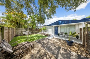 Ein Wohnhof mit Terrasse, Holzzaun, Hängematte und verschiedenen Pflanzen.