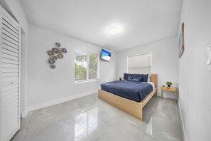 A bedroom with a bed, a TV, and a window with blinds. - Stylish 4-Bedroom Villa Sleeps 12 | Near FLL and the Beaches (Fort Lauderdale)