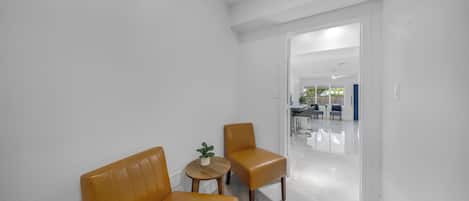 A modern, minimalist room with two leather chairs, a small wooden table, and a potted plant.