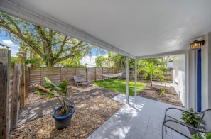 A covered patio area with a wooden fence, a hammock, a bench, and a potted plant. - Stylish 4-Bedroom Villa Sleeps 12 | Near FLL and the Beaches (Fort Lauderdale)
